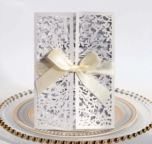 Macro view of laser-cut leaf patterns and a cream satin ribbon on a wedding card