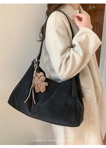 Modelo con un gran bolso tote de ante negro y un adorable oso de peluche marrón