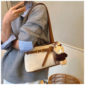 Detail of leopard print bucket bag with brown leather trim and cute teddy bear charm