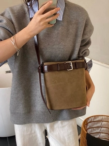 Khaki suede bucket bag featuring brown leather belt buckle detail and shoulder strap