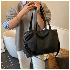 Detailed view of spacious black canvas tote bag with premium leather handles and metal zipper