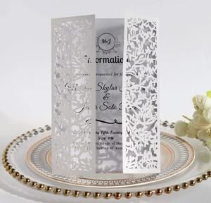 Detailed laser-cut floral wedding invitation with M+J initials on a white card
