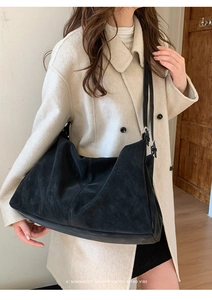 Bolso hobo negro grande y minimalista al hombro con un elegante abrigo beige