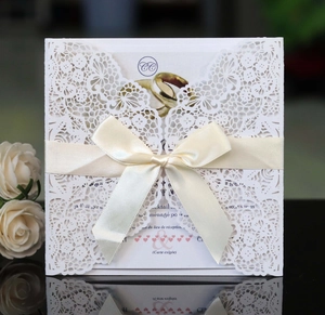Détail d'invitation de mariage en dentelle découpée au laser avec ruban et décor floral