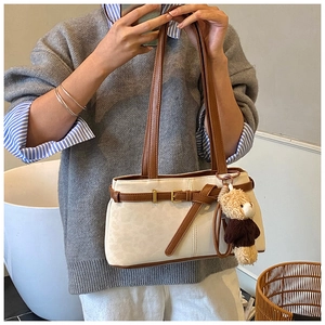 Detail of off-white vintage bucket bag with brown straps and cute teddy bear charm accessory
