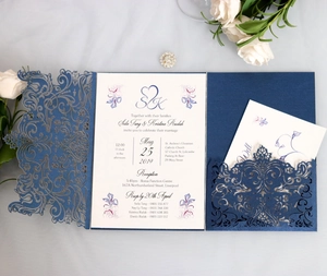 Detail of laser-cut navy wedding invitation with intricate lace floral pattern