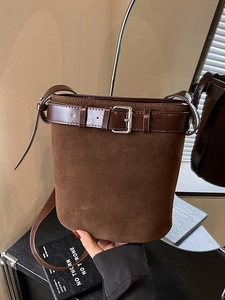 Minimalist dark brown suede bucket bag with leather belt buckle and silver hardware details