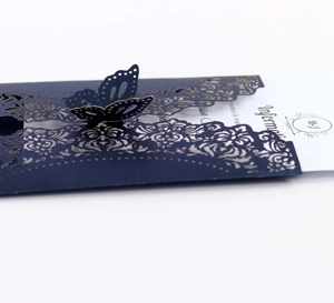 Detail of laser-cut navy blue wedding invitation with 3D butterfly and floral patterns