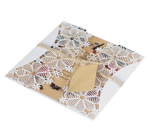 Detail of laser-cut invitation sleeve with floral kraft paper insert and hemp rope