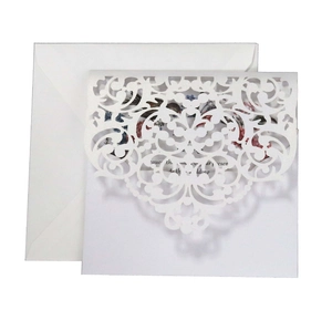 Detail of laser-cut floral wedding invitation set with elegant lace pattern and envelope