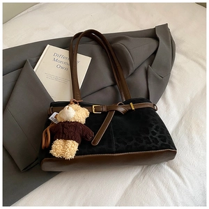 Detail of leopard print bucket bag with brown leather trim and cute bear charm pendant