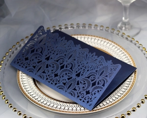 Detail of laser-cut navy invitation featuring intricate floral patterns and silver band