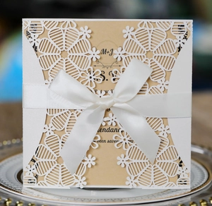 Laser cut wedding invitation with white floral lace sleeve and satin ribbon bow detail