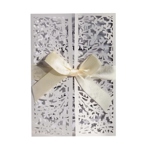 Elegant white laser-cut wedding invitation with a floral pattern and silk ribbon bow
