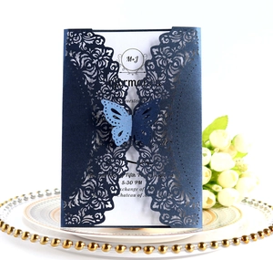 Detail of laser-cut floral wedding invitation with butterfly clasp on decorative plate