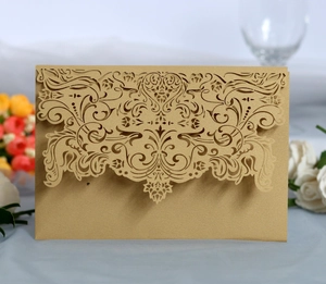 Close-up of champagne gold laser-cut wedding invitation with intricate floral patterns