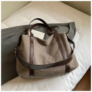 Detail of taupe canvas tote bag featuring brown leather handles and adjustable shoulder strap