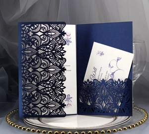 Navy blue laser-cut wedding invitation with intricate floral lace and white insert card