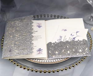 Detailed view of silver glitter laser-cut lace wedding invitation with floral insert