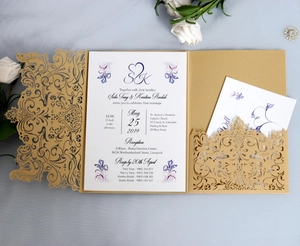 Detail of laser-cut floral invitation cover with printed inner cards on marble background