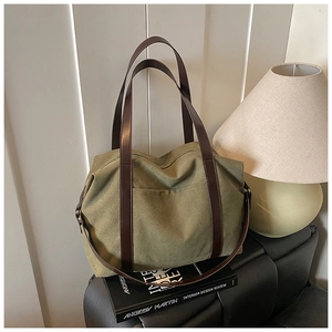 Detail of olive green canvas tote bag with brown straps placed on a decorative book