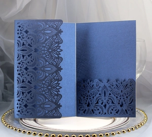 Close-up of laser-cut navy blue wedding invitation card with intricate hollow lace pattern