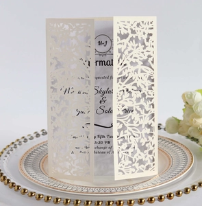 Laser-cut floral wedding invitation with M+J initials on a white ceramic tray