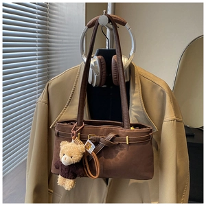 Detail of vintage dark brown leather shoulder bag with buckle and teddy bear charm