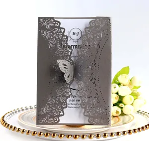 Close-up of laser-cut floral wedding invitation with grey pearlescent paper and butterfly