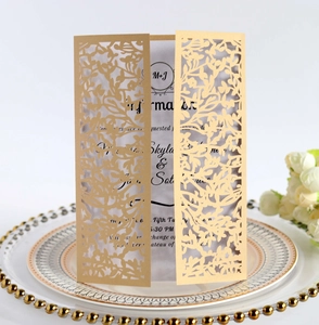 Detailed close-up of champagne gold laser-cut wedding invitation with vine pattern