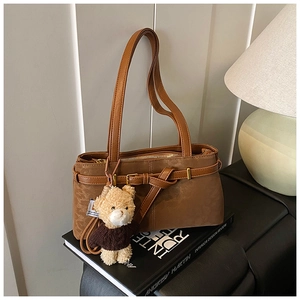Close-up of retro brown shoulder bag with leopard accent and teddy bear charm decor