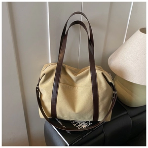 Detail of large canvas tote bag with brown straps on a premium black leather surface