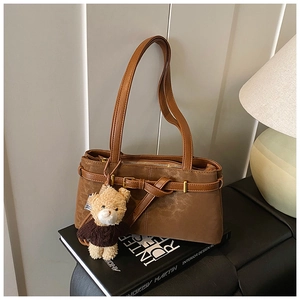 Detail of vintage matte brown shoulder bag with decorative buckle and cute bear pendant