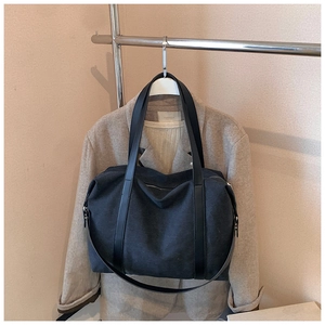 Detail view of a large black canvas tote bag hanging on a rack for fashion styling