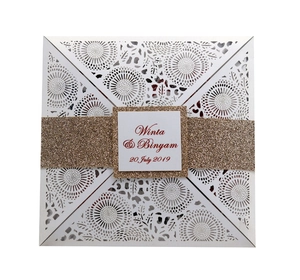 Detail of white laser-cut floral wedding invitation with a gold glitter belly band