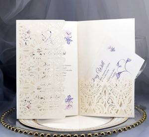 Detail of laser-cut lace wedding invitation with floral insert on elegant white plate