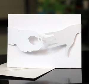 Detailed 3D laser-cut white wedding invitation card showing a hand putting on a ring