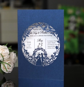 Macro view of laser-cut wedding invitation featuring intricate bird and floral patterns