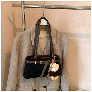 Detail of leopard print suede bucket bag with decorative brown belt and plush bear charm