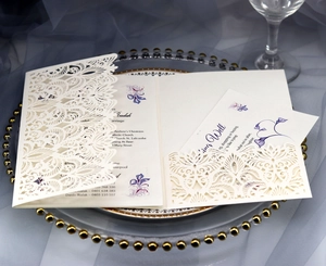 Detail of laser-cut lace wedding invitation with ivory insert and floral graphics
