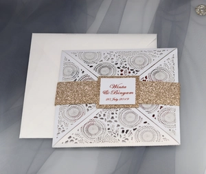 Detailed laser-cut white wedding invitation with gold glitter band and floral patterns