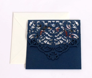 Close-up of laser-cut navy blue wedding invitation with pearlescent floral pattern