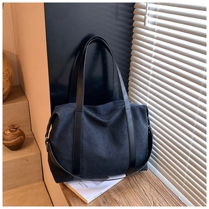 Detail of black canvas tote bag texture with leather straps in natural window light