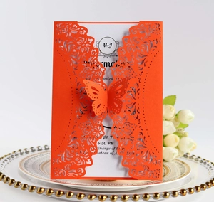 Detail of laser-cut wedding invitation with orange floral pattern and 3D butterfly