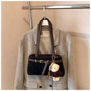 Detail of leopard print suede bucket bag with leather strap and plush bear charm