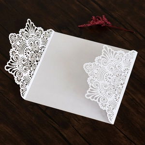 Gros plan d'une invitation de mariage en dentelle blanche découpée au laser sur bois