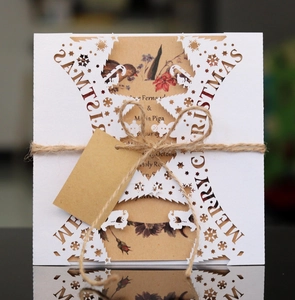Macro detail of laser-cut Merry Christmas card with snowflake patterns and twine tie