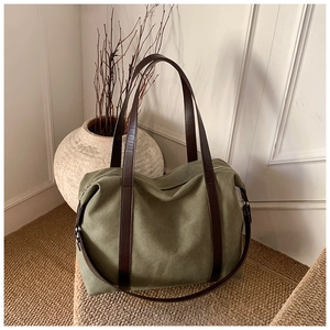 Detail of olive green canvas tote bag with brown leather straps on woven rug