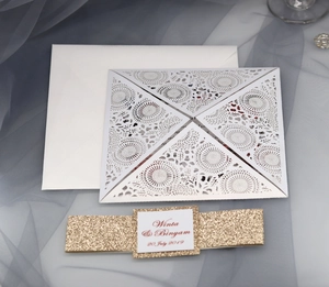 Detail of laser-cut wedding invitation set with elegant white envelope and gold glitter band