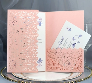 Close-up of laser-cut wedding invitation with pearl pink hollow pattern and inner card